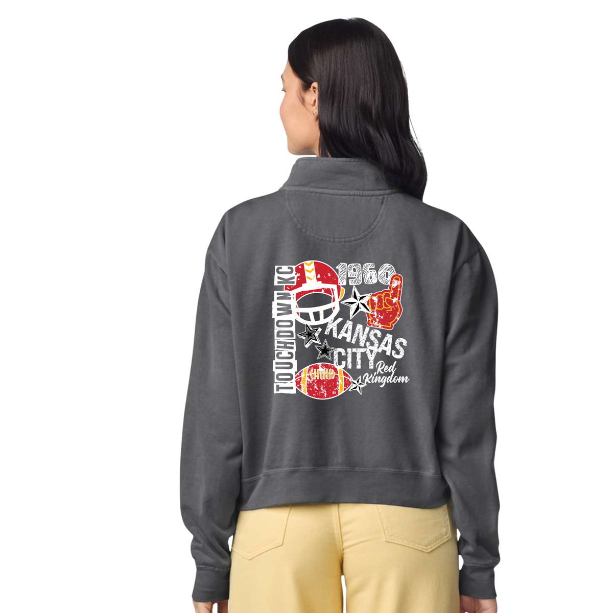 A woman shown from the back wearing a dark gray cropped quarter-zip hoodie with a large red, white, and black graphic on the back, paired with tan pants, against a plain white background.