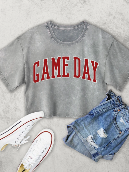 Gray t-shirt with 'GAME DAY' text, white sneakers, and denim shorts on a light gray background