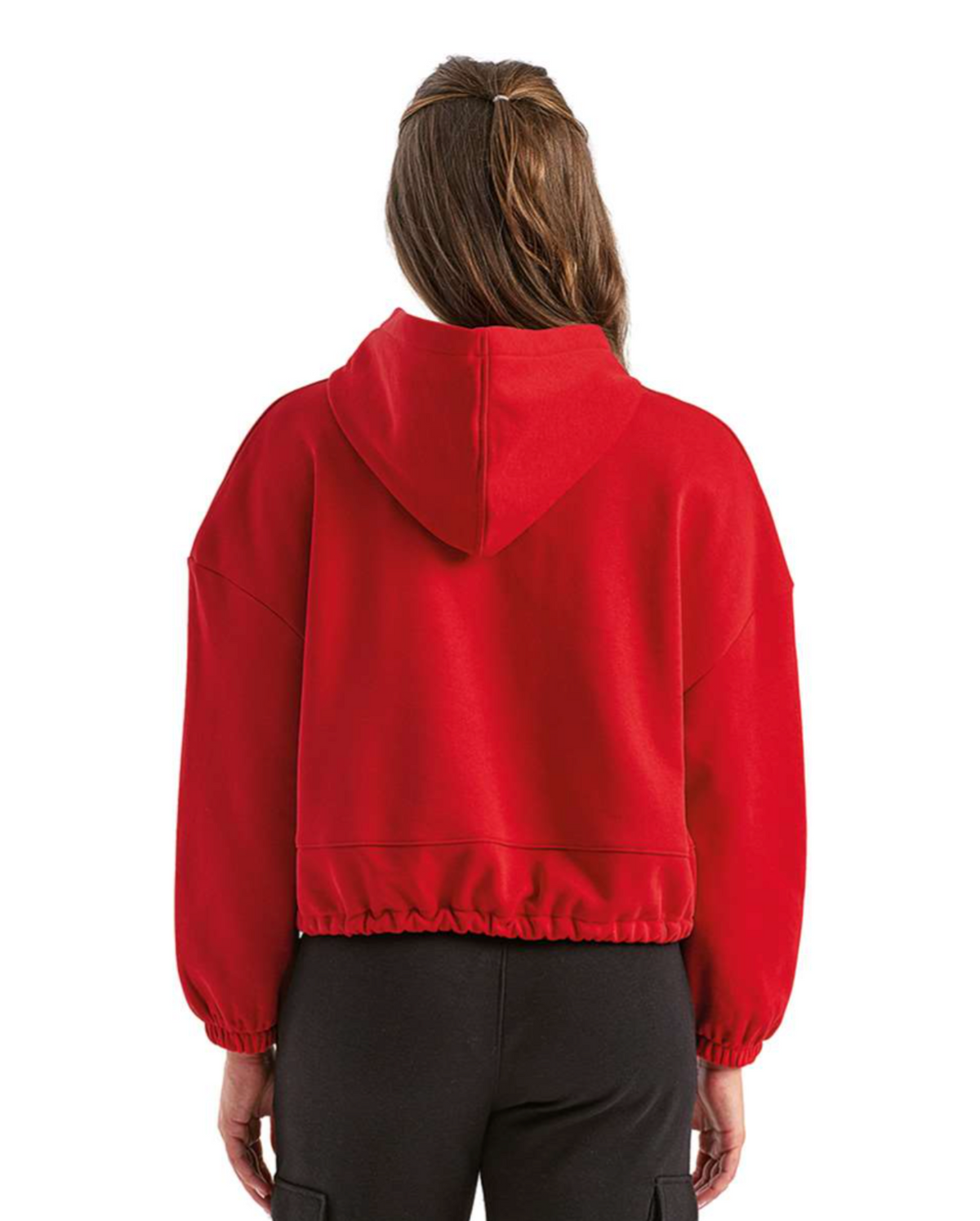 A person viewed from the back wearing a bright red cropped hooded sweatshirt and dark pants against a plain white studio background.